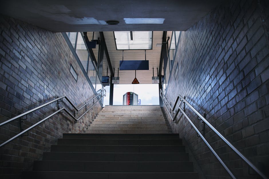 A night scene at Belsize Park train station showing the platform with tactile paving and yellow safety lines along the edge. A blue and white train is stationary on the left side, with illuminated win
